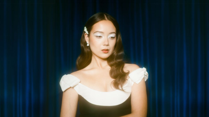 The jazz artist Laufey in a black and white dress looking down. Image credits: Pinterest